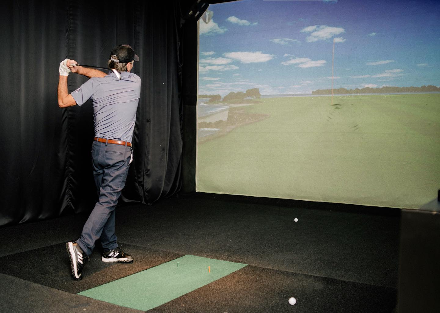 A man tees off at a North Swing Golf Simulator